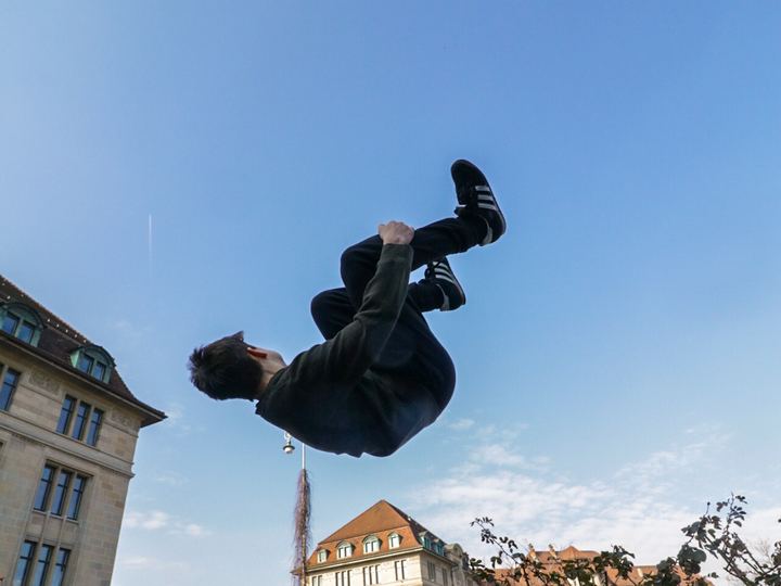 A trained freerunner performing a sideflip above concrete in Zurich
