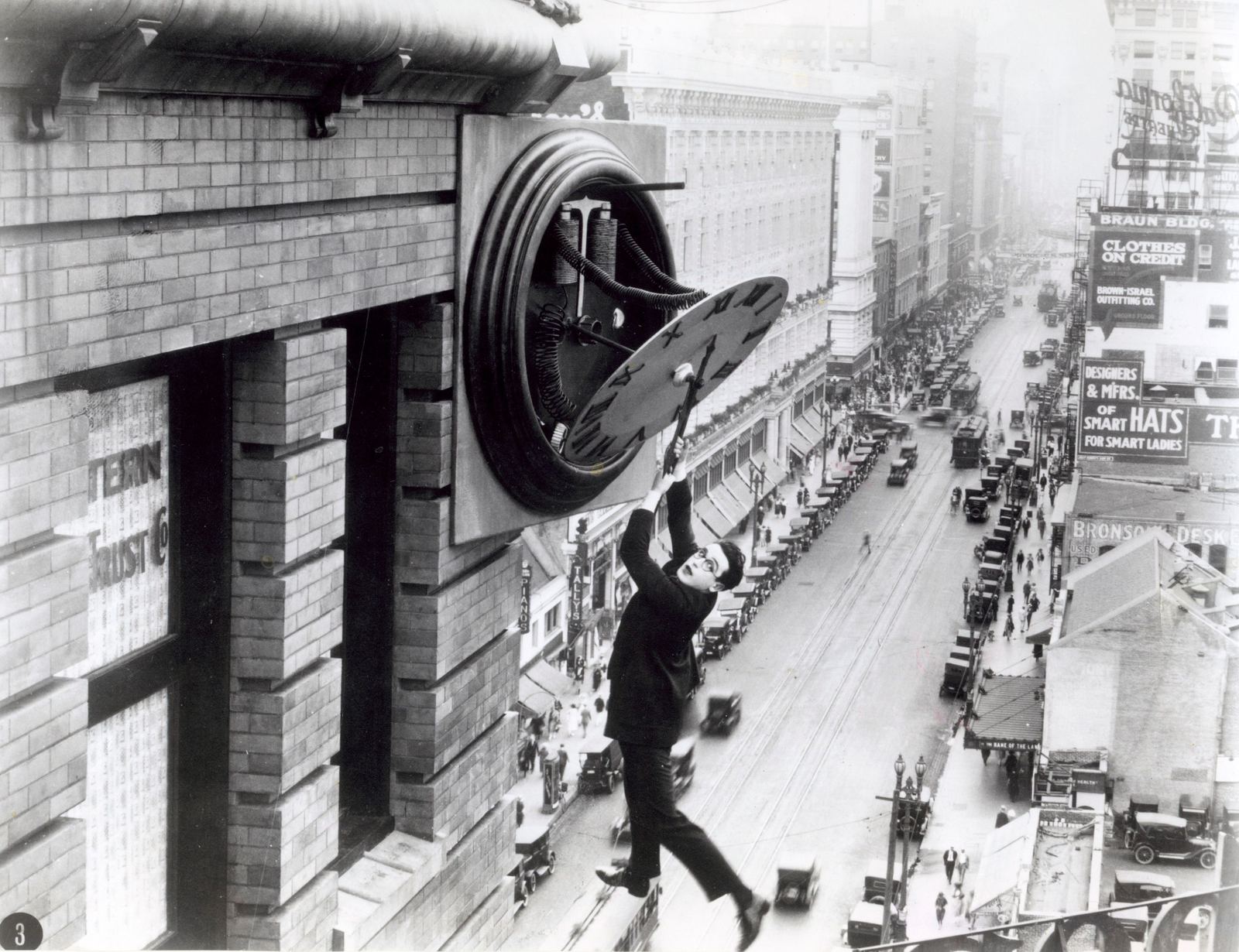 Harold Lloyd hanging from a giant clock above a city street in Safety Last